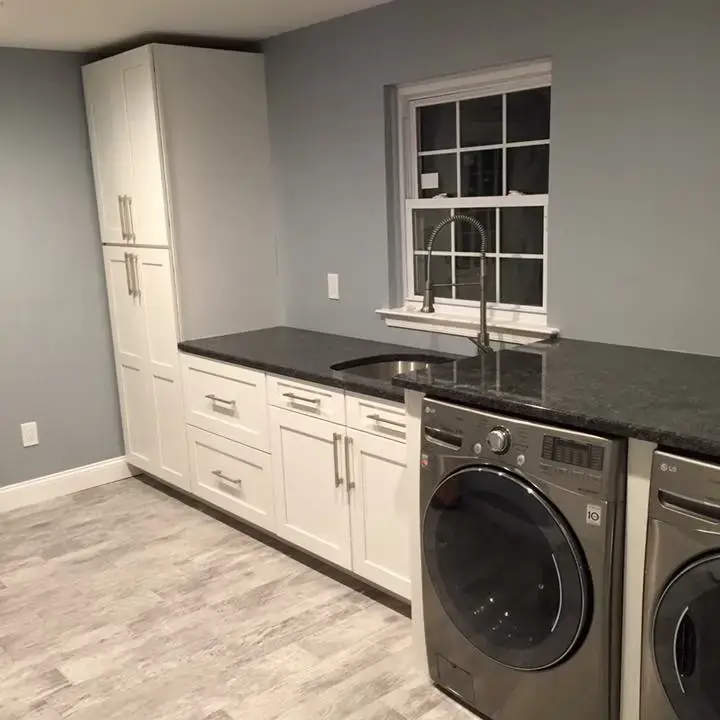 Basement laundry room with washer, cabinets, and countertop.