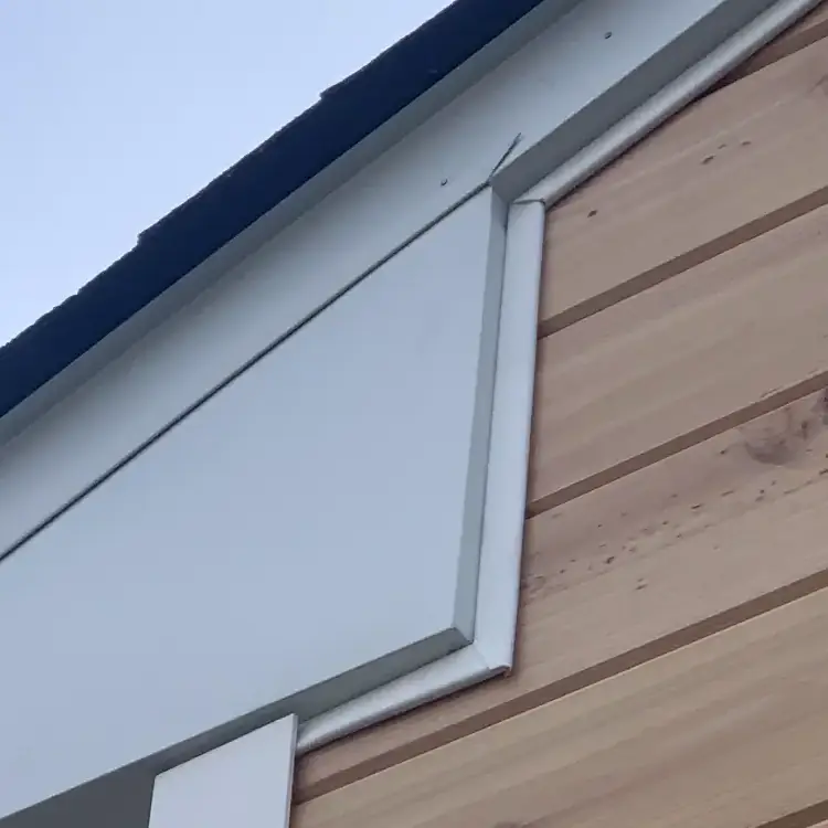 Close-up of house roof corner, wooden siding.