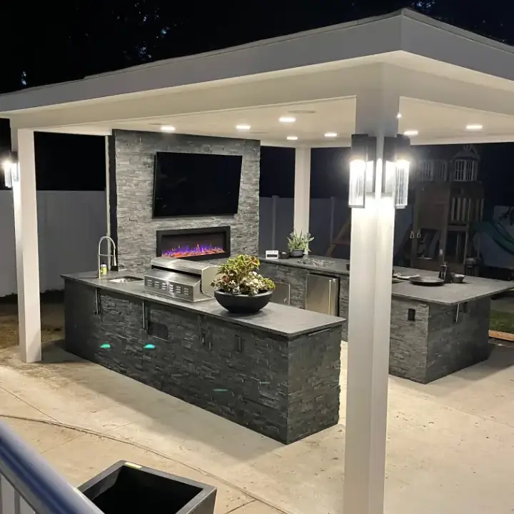 Outdoor kitchen with stone countertops and lighting.