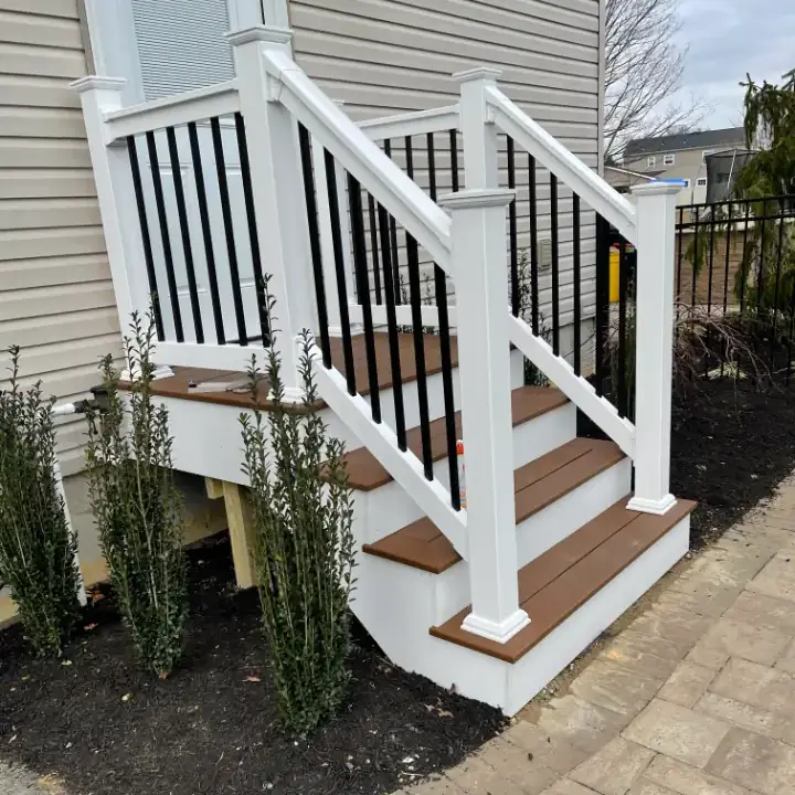Outdoor stairs with black railing and white posts.