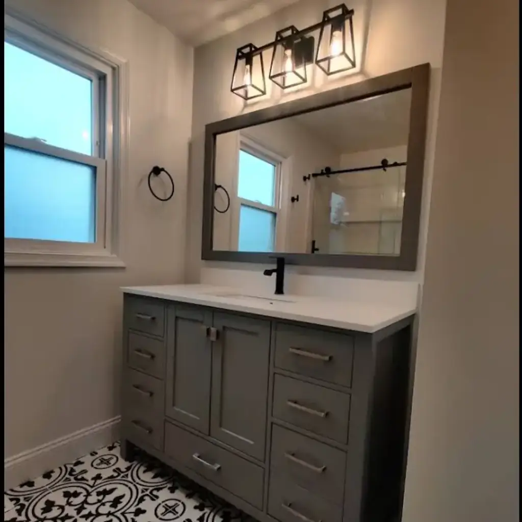 Modern bathroom with large mirror and elegant lighting.