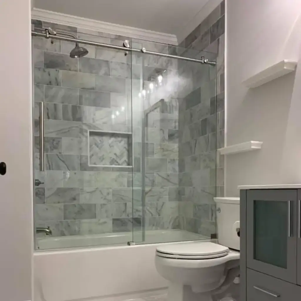 Modern bathroom with marble tile and glass shower door.