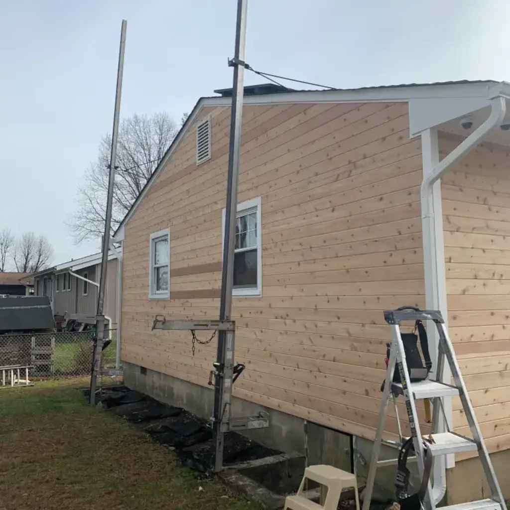 Wooden house exterior with ladder and poles nearby.