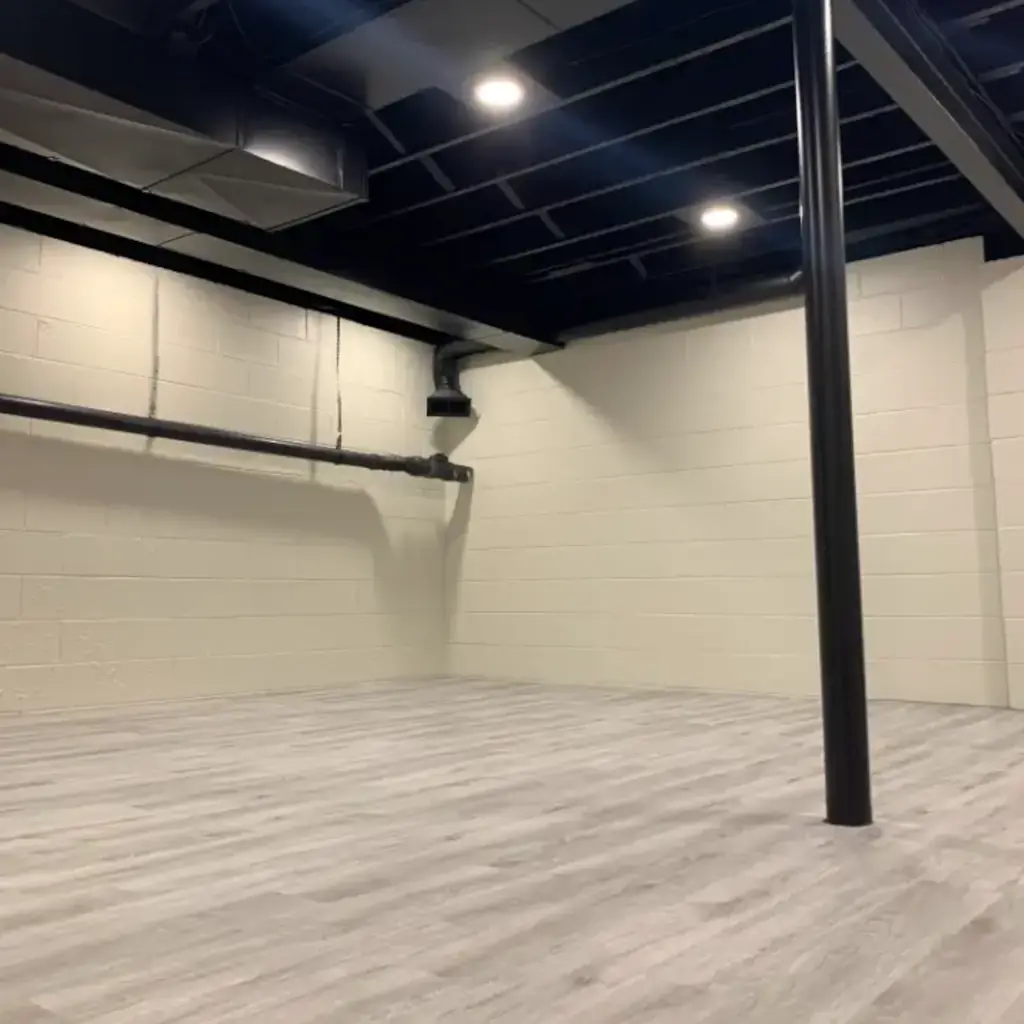 Modern finished basement with exposed beams and pipes.