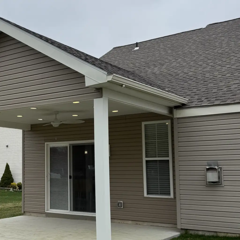 Backyard patio under roof with sliding glass door.